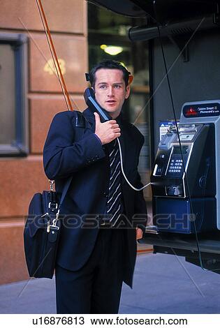 Stock Image - Businessman talking on pay phone. Fotosearch