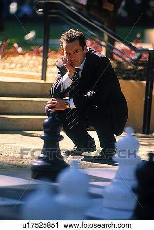 Stock Image - Businessman watching a huge game a chess. Fotosearch