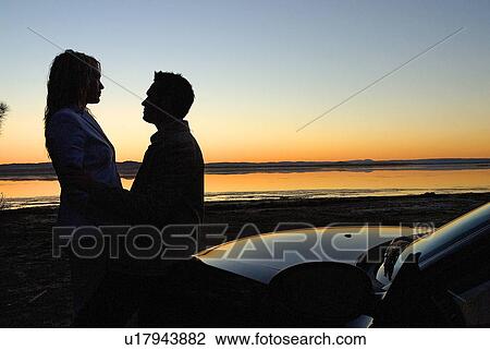 Couple at sunset on a beach View Large Photo Image Stock Image - Couple at sunset on a beach. Fotosearch