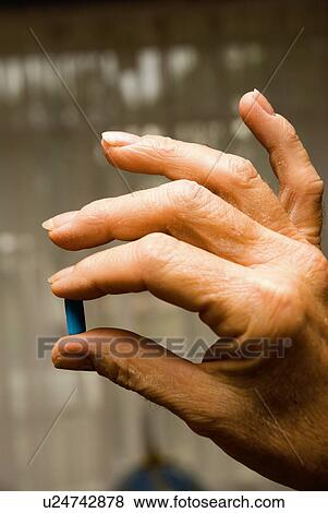 Stock Photo - Elderly hand with capsule. Fotosearch