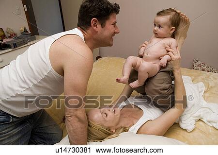 Stock Image - Family playing with baby. Fotosearch