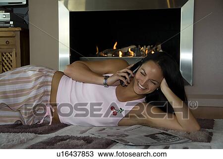 Stock Image - Home fireplace and woman on the phone. Fotosearch