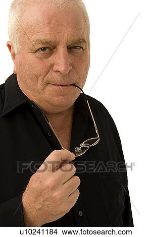 Picture - Mature man chewing on glasses. Fotosearch