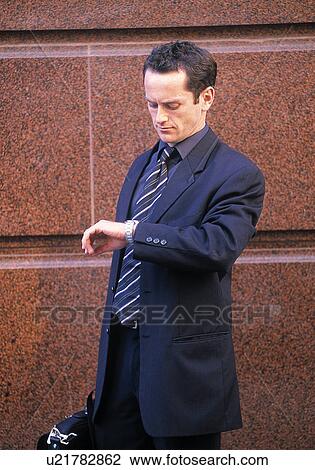 Stock Image - Outdoor businessman looking at his watch. Fotosearch