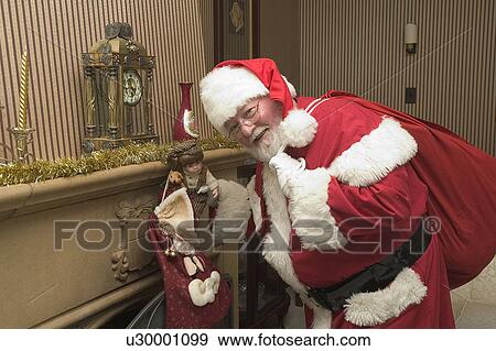 Stock Photo - Santa filling stockings. Fotosearch