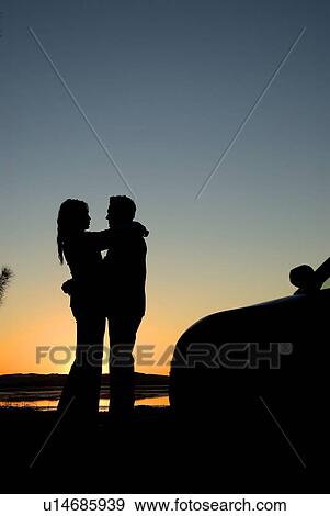 Stock Photo - Silhouette lovers at sunset on a beach. Fotosearch