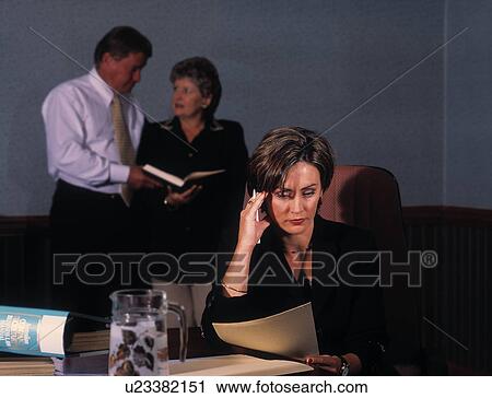 Stock Image - Stressed businesswoman with business people in the background. Fotosearch