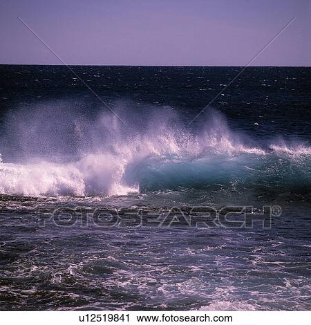 Stock Image - Wave breaking at beach. Fotosearch