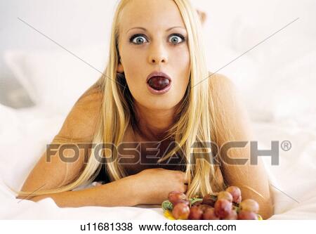 Stock Photo - Woman in bed eating grapes. Fotosearch