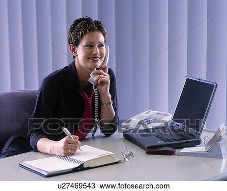Woman sitting at desk laptop talking on telephone View Large Photo Image Stock Image - Woman sitting at desk laptop talking on telephone. Fotosearch