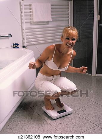 Woman weighing in on a scale in the bathroom View Large Photo Image Stock Photo - Woman weighing in on a scale in the bathroom. Fotosearch