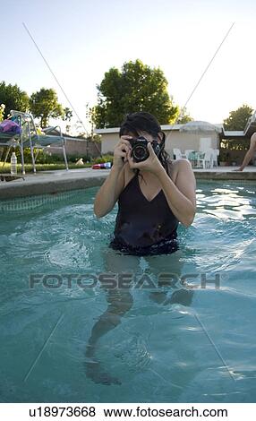 Stock Photo - A female taking a picture while in the pool. Fotosearch