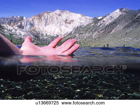 A hand in the water with a mountain in the background View Large Photo Image Stock Photography - A hand in the water with a mountain in the background. Fotosearch