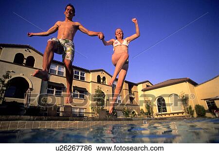 A happy young couple leaps into a swimming pool during a hot summer day View Large Photo Image Stock Photograph - A happy young couple leaps into a swimming pool during a hot summer day. Fotosearch