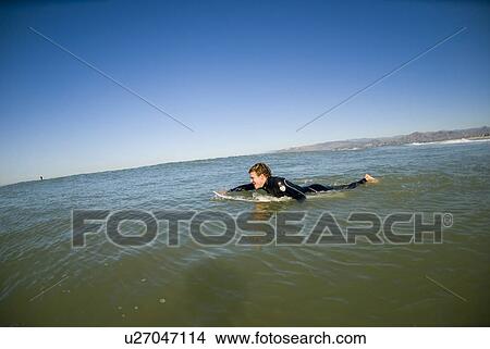 Picture - A male surfer paddling out. Fotosearch