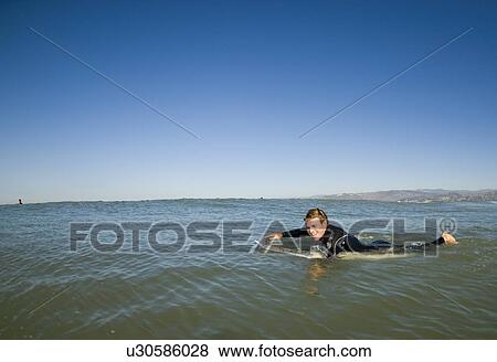 Stock Photo - A male surfer paddling out. Fotosearch