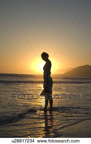 Picture - A young female on the beach at sunset. Fotosearch