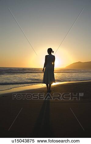 Stock Photography - A young female on the beach at sunset. Fotosearch