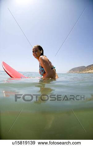 Stock Photo - A young surfer girl out in the ocean. Fotosearch