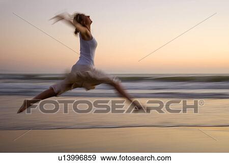 A young woman dances ballet on the beach at sunset View Large Photo Image Stock Photo - A young woman dances ballet on the beach at sunset. Fotosearch