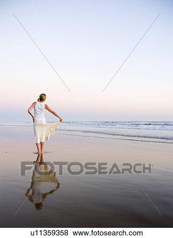A young woman poses on the beach at sunset View Large Photo Image Stock Photo - A young woman poses on the beach at sunset. Fotosearch