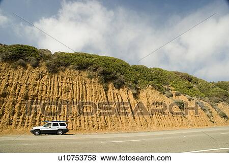 Stock Photo - An SUV parked on the side of the highway at the Ventura County line with a surfboard on top California USA. Fotosearch