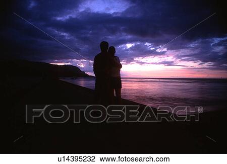 Stock Image - Couple watching the sunset Hanalei Bay Princeville Kauai Hawaii USA. Fotosearch