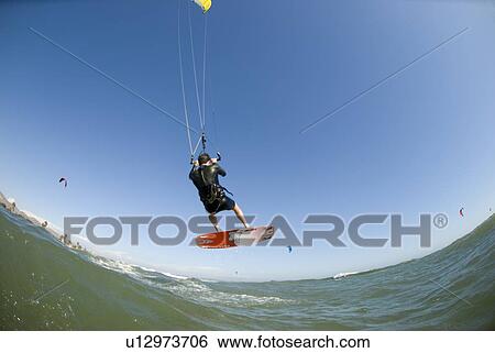 Stock Photograph - Extreme kite surfer in the air over the water. Fotosearch