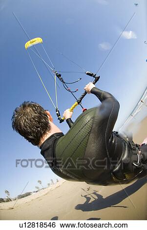 Stock Photograph - Extreme kite surfer on the beach. Fotosearch