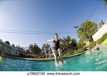 Stock Image - Female diving into an outdoor home pool. Fotosearch