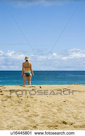 Stock Image - Female in a green bathing suit on the beach. Fotosearch