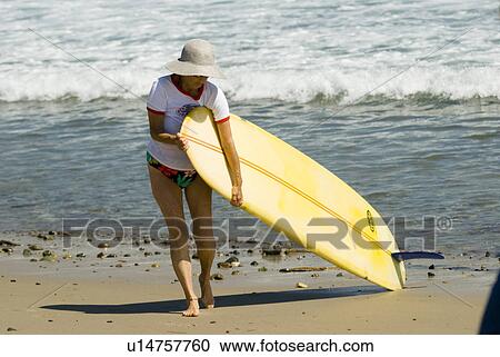 Stock Image - Lady with surf board. Fotosearch