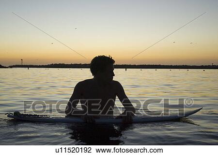 Male surfer in the water after sunset. View Large Photo Image Stock Image - Male surfer in the water after sunset.. Fotosearch
