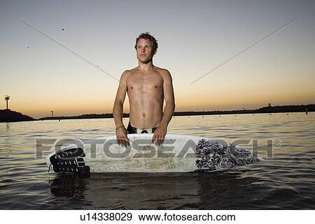 Male surfer in the water after sunset View Large Photo Image Stock Photo - Male surfer in the water after sunset. Fotosearch