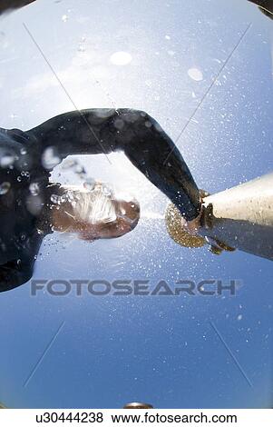 Stock Photo - Male surfer rinsing off at a shower. Fotosearch