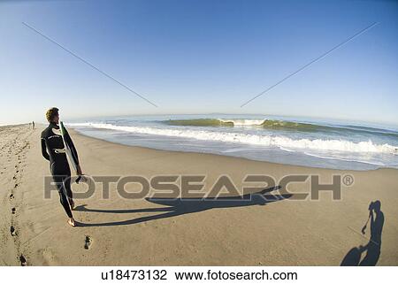 Male surfer waking down the beach View Large Photo Image Stock Image - Male surfer waking down the beach. Fotosearch