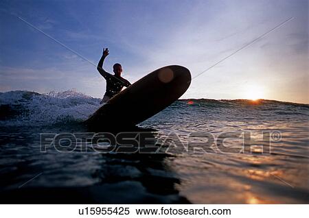 Stock Photography - Male turns on a wave at sunset. Fotosearch
