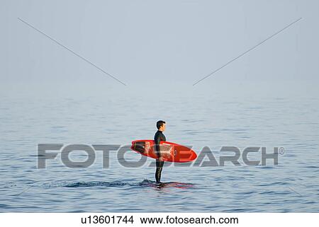 Picture - Male with a red surfboard. Fotosearch