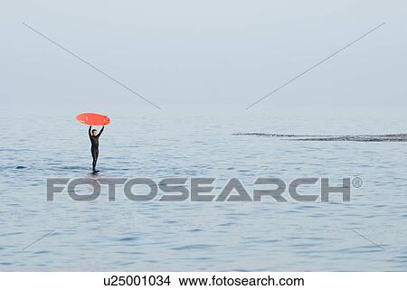 Picture - Male with a red surfboard. Fotosearch
