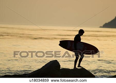 Male with a surfboard at sunset View Large Photo Image Stock Photo - Male with a surfboard at sunset. Fotosearch
