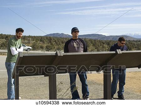 Men looking at a park sign in the Mountains View Large Photo Image Stock Photo - Men looking at a park sign in the Mountains. Fotosearch