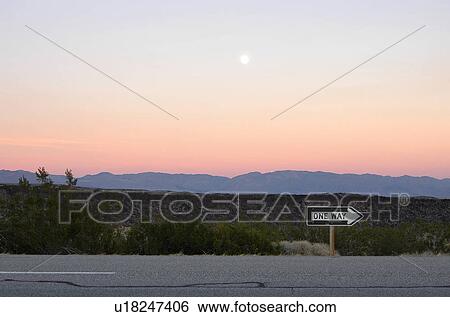 Stock Photograph - One way road with mountains in the background. Fotosearch
