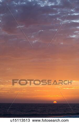 Stock Image - Sunset setting in the ocean. Fotosearch