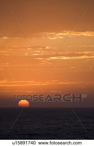 Stock Image - Sunset setting in the ocean. Fotosearch
