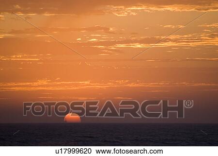 Stock Image - Sunset setting in the ocean. Fotosearch