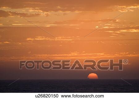 Stock Image - Sunset setting in the ocean. Fotosearch