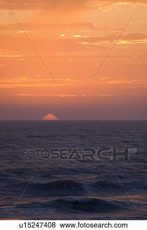 Stock Photo - Sunset setting in the ocean. Fotosearch