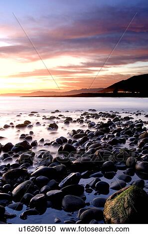 Stock Image - Sunset with rocks and mountains. Fotosearch