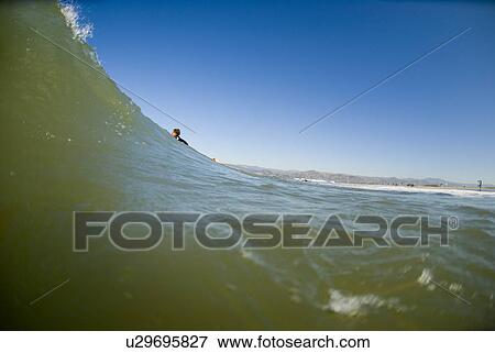 Stock Photo - Surfer laying on surfboard. Fotosearch