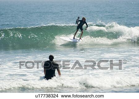 Picture - Surfers in the water. Fotosearch